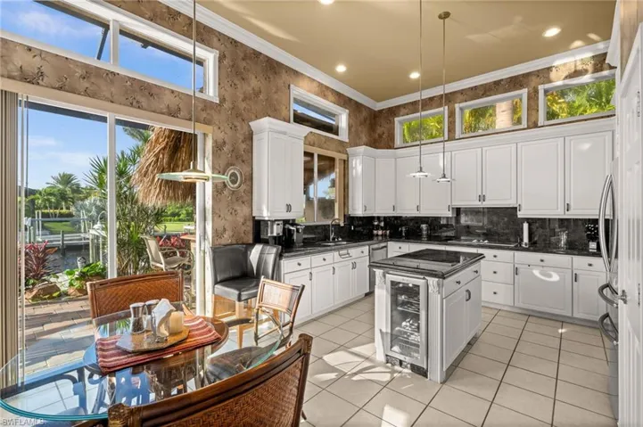 Kitchen featuring light tile patterned floors, hanging light fixtures, beverage cooler, tasteful backsplash, and wallpapered walls