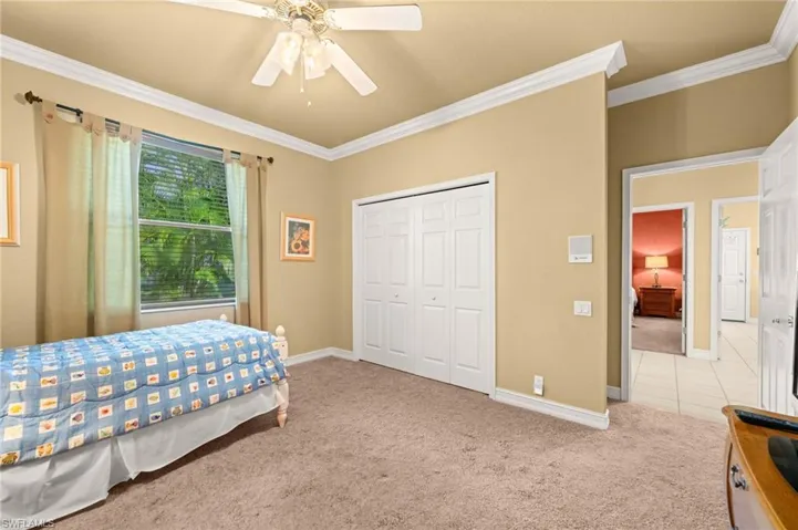 Bedroom featuring crown molding, light colored carpet, ceiling fan, and a closet