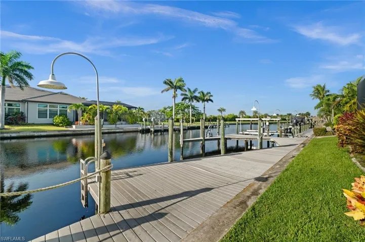 Dock area with a water view, boat lift, and a yard