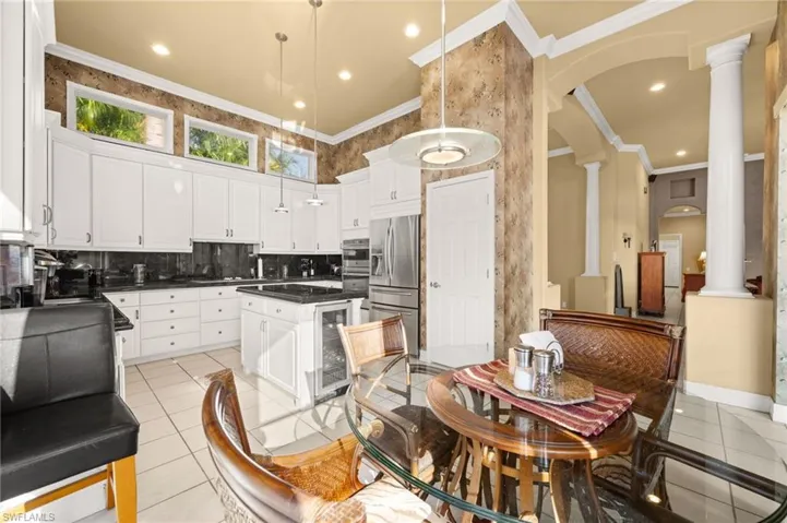 Kitchen featuring arched walkways, crown molding, white cabinets, wine cooler, and stainless steel refrigerator with ice dispenser