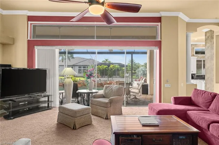 Living room featuring ornamental molding, ceiling fan, carpet floors, and arched walkways