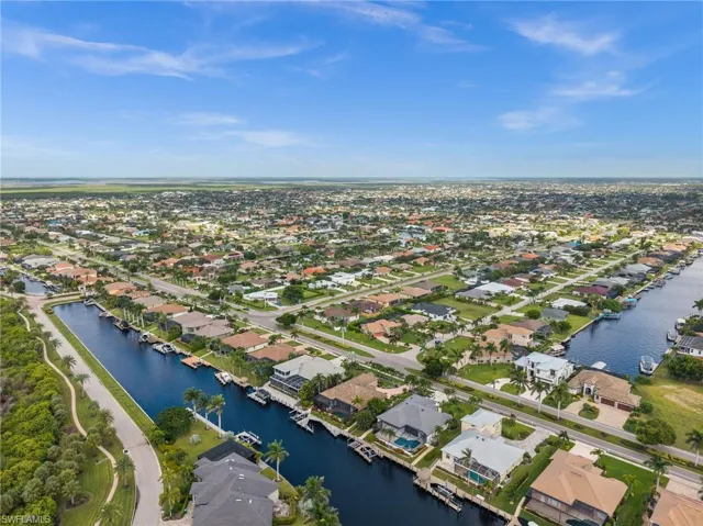 Aerial view of property and surrounding area featuring a nearby body of water and nearby suburban area
