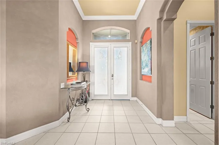 Entryway featuring ornamental molding, french doors, light tile patterned floors, and arched walkways