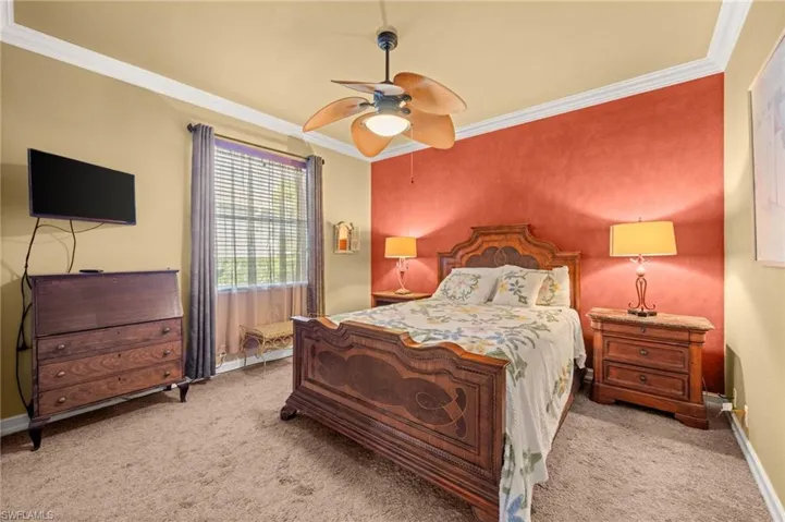 Bedroom with ornamental molding, ceiling fan, and carpet floors