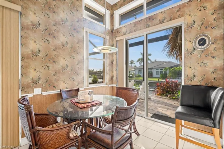 Tiled dining space featuring wallpapered walls and a towering ceiling