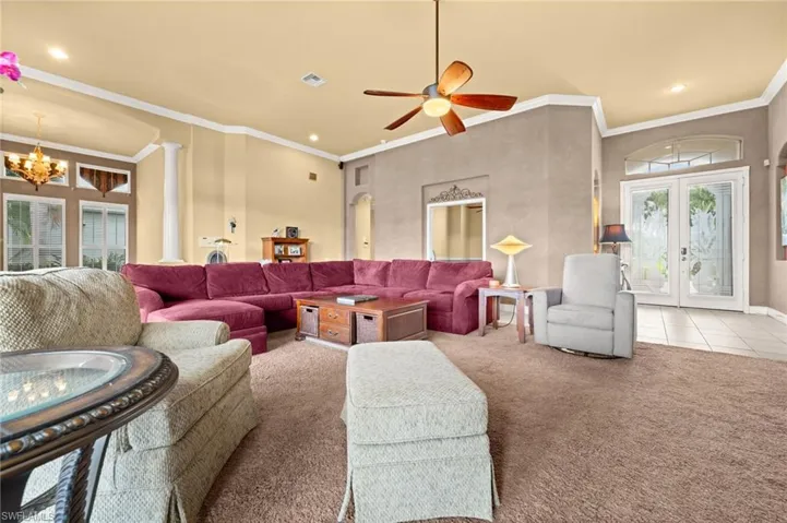 Carpeted living area with crown molding, a chandelier, recessed lighting, french doors, and tile patterned floors
