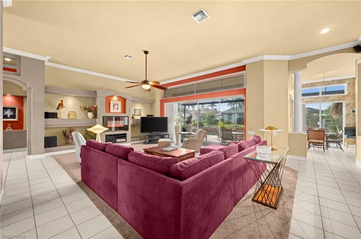 Living room featuring arched walkways, light tile patterned floors, ornamental molding, ceiling fan, and recessed lighting