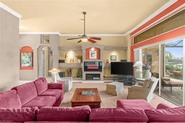 Living area featuring crown molding, a fireplace, carpet floors, and ceiling fan