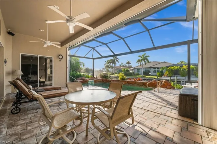 View of patio featuring a lanai, a sunroom, ceiling fan, a residential view, and outdoor dining space