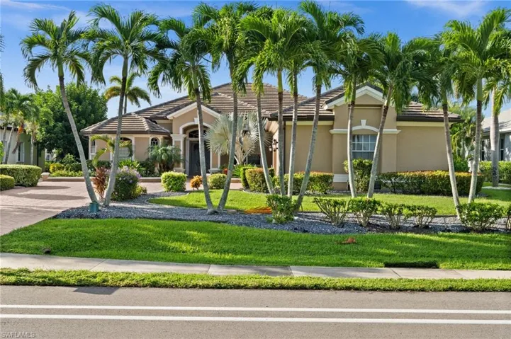 View of front of home with stucco siding, a front yard, and a tiled roof