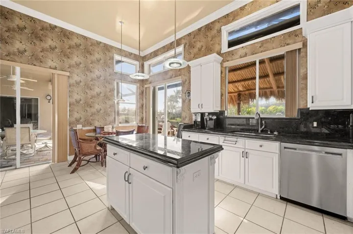 Kitchen featuring wallpapered walls, white cabinetry, dishwasher, dark stone countertops, and crown molding