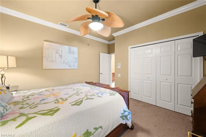 Carpeted bedroom with ornamental molding, a ceiling fan, and a closet