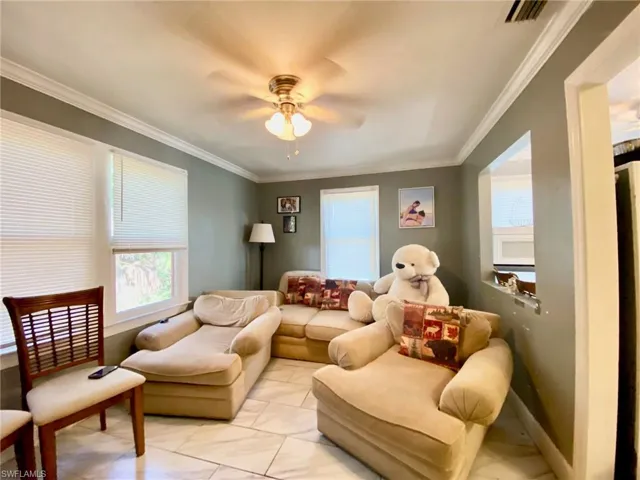 Living room with light tile patterned flooring, ornamental molding, and ceiling fan
