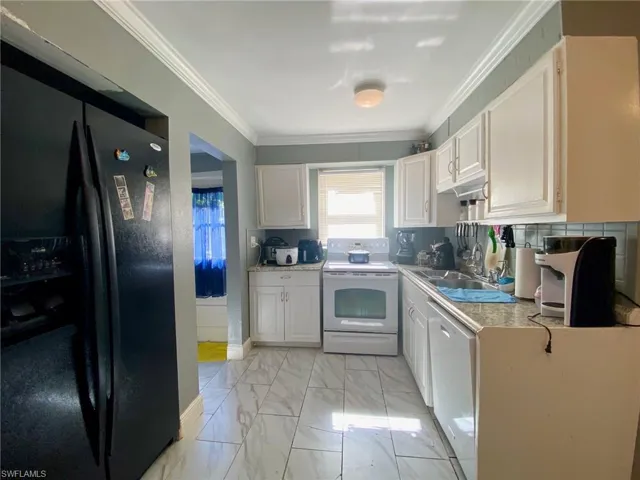 Kitchen featuring white cabinetry, white appliances, ornamental molding, sink, and light tile patterned floors