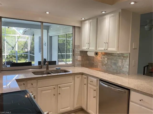 Kitchen featuring light stone countertops, white cabinets, dishwashing machine, tasteful backsplash, and recessed lighting