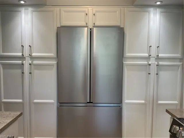 Kitchen featuring white cabinets, freestanding refrigerator, and recessed lighting