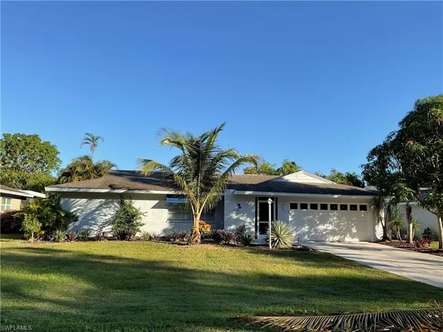 Ranch-style house with a front yard, an attached garage, driveway, and a shingled roof