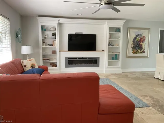 Living room featuring stone tile floors, ceiling fan, and a fireplace