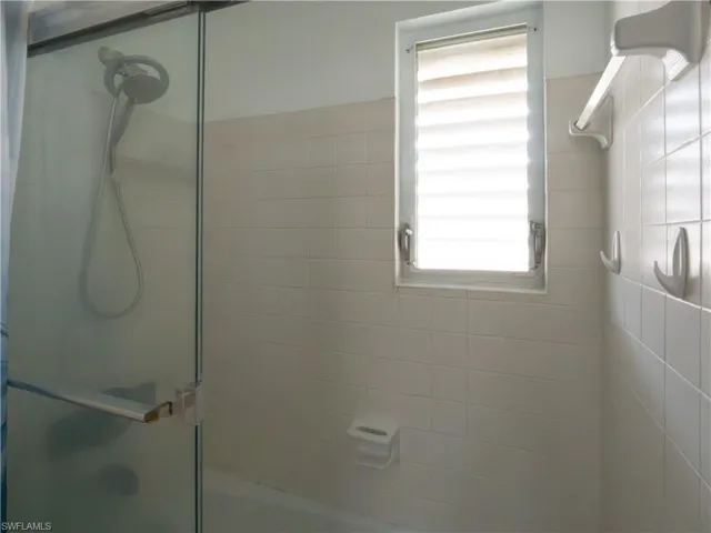 Shower enclosure with a clear glass panel and an integrated handheld showerhead