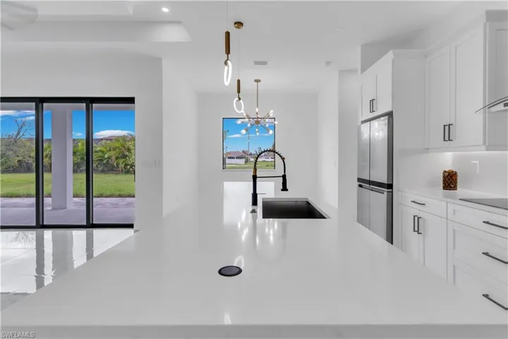 Kitchen with a healthy amount of sunlight, sink, stainless steel fridge, and a chandelier