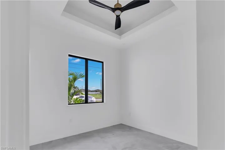 Empty room with ceiling fan and a tray ceiling