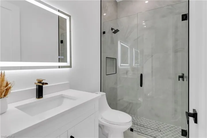 Bathroom with vanity, a shower with shower door, and toilet