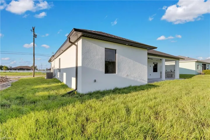 Rear view of house with central AC and a yard