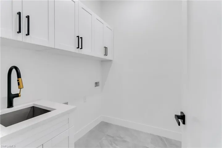 Laundry area with hookup for a washing machine, cabinets, sink, and electric dryer hookup