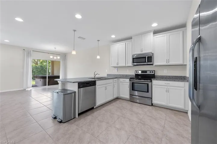 Kitchen with stainless steel appliances, hanging light fixtures, light tile floors, and kitchen peninsula