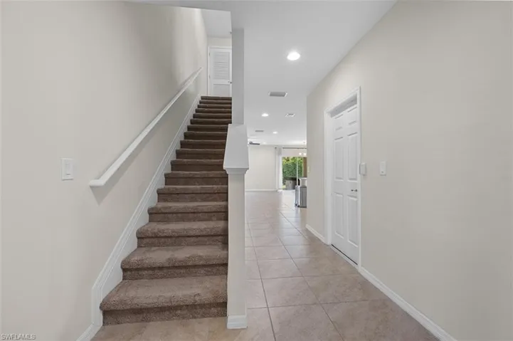 Staircase leading to bedrooms entryway with light tile flooring