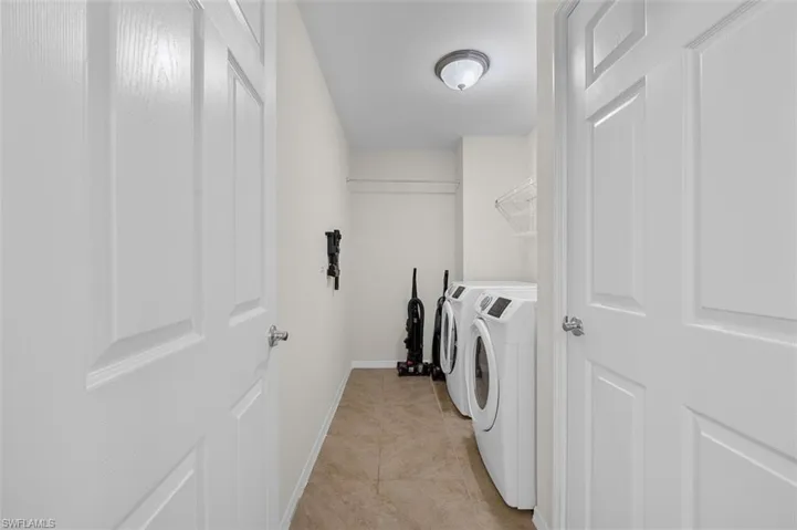 Washroom with washer and dryer and light tile floors