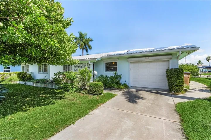 View of front of house with a large shade tree in front yard (highly unusual in Florida) but great to ward off the west sun blaze of summer and deep 1 car garage with lots of storage room and rear exit door. Easy to access boat gear