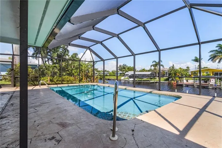 View of heated pool with screen enclosure, a water view, and a patio area with new Pool Cage in 2023