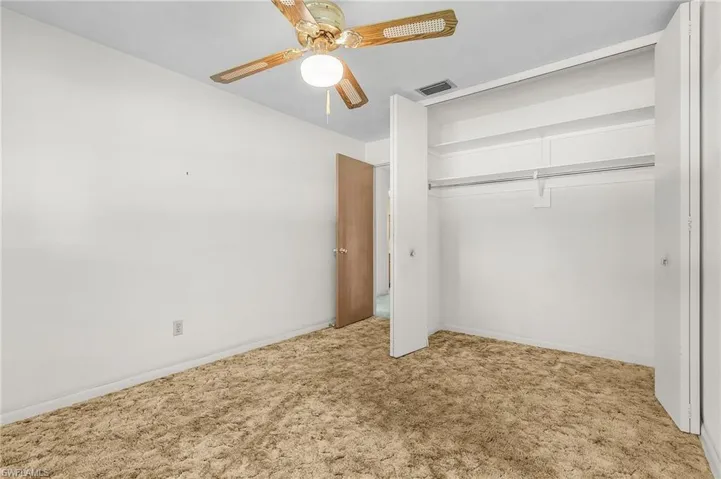 Unfurnished bedroom number 2 with light carpet, double closet, and ceiling fan