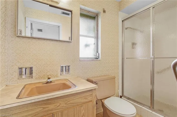 Bathroom with vanity, toilet, and a shower with sliding doors and tile floor