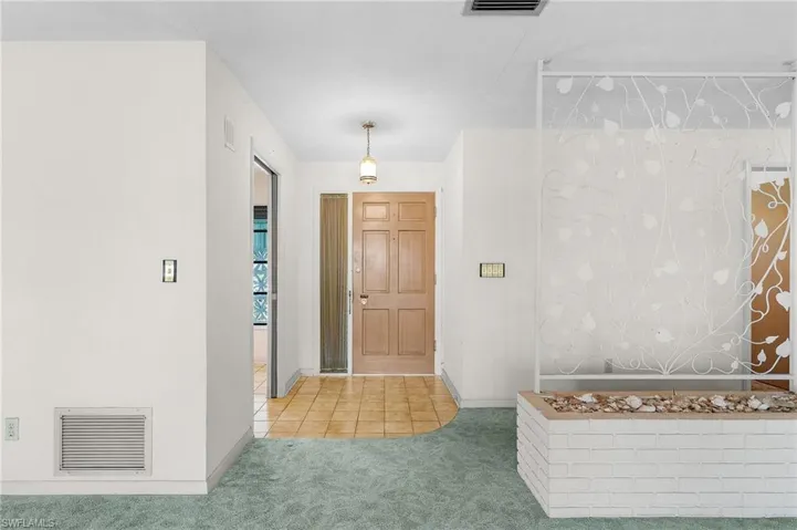 Foyer entrance with tile floor and side light window and storm screen door as well as roll down hurricane protection