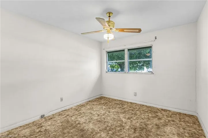 Bedroom number 2 featuring carpet flooring and ceiling fan and roll down hurricane shutters and double closet