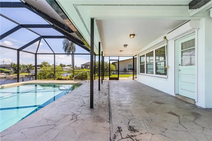 View of swimming pool featuring a patio, a water view, and a covered lanai with door from the Florida room...all windows have roll down hurricane shutters
