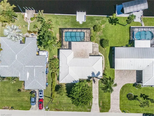 Drone / aerial view shows well maintained roof, new pool cage, cantilever dock
