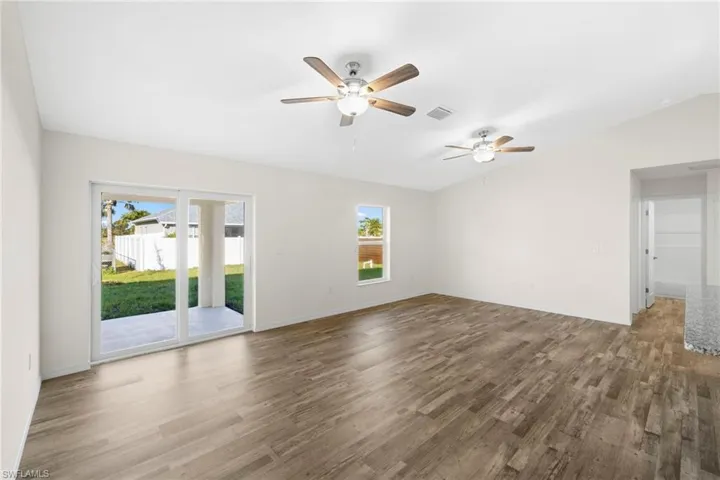 Unfurnished room with wood finished floors, vaulted ceiling, and ceiling fan
