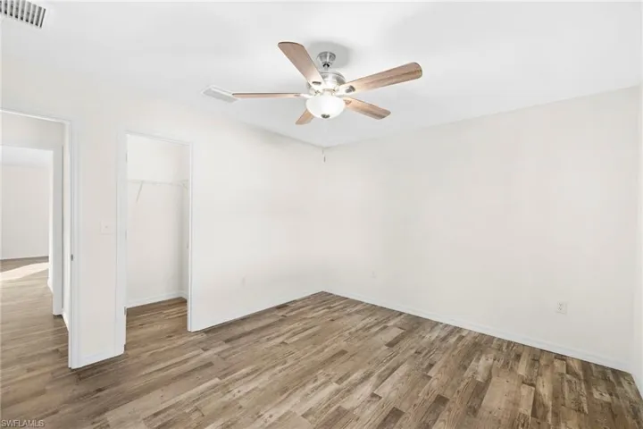 Unfurnished bedroom with light wood-style floors, a walk in closet, and a ceiling fan
