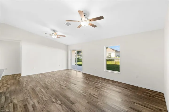 Empty room with vaulted ceiling, wood finished floors, and a ceiling fan
