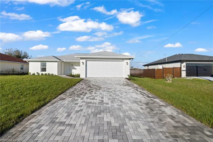 View of front of property with a front lawn, decorative driveway, an attached garage, and stucco siding