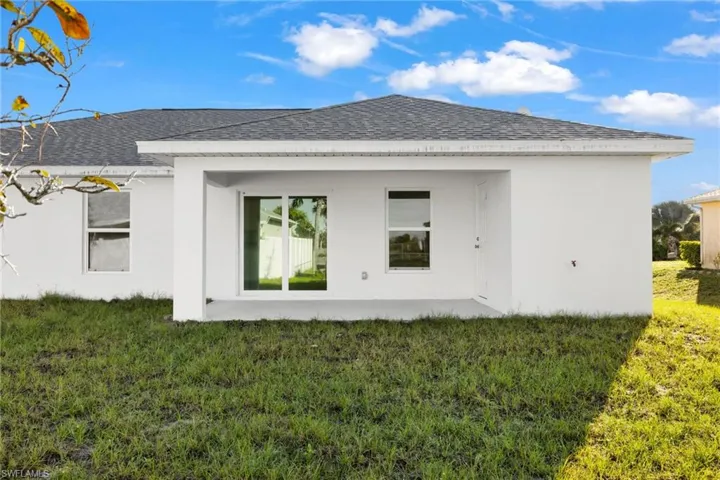 Back of house featuring a shingled roof, a yard, stucco siding, and a patio area