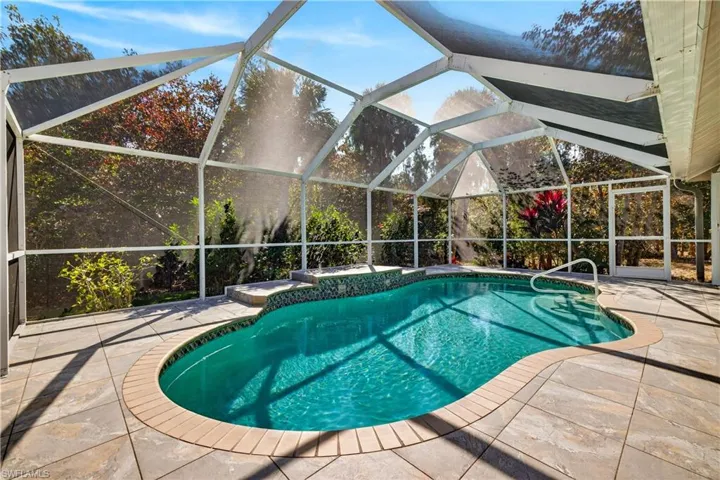 Outdoor pool with glass enclosure, a sunroom, and a patio area