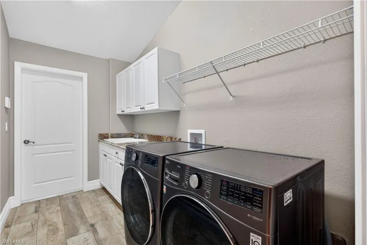 Laundry room featuring a textured wall, light wood-type flooring, cabinet space, and washing machine and clothes dryer