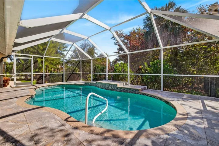 Swimming pool with glass enclosure, a sunroom, a hot tub, and a patio area