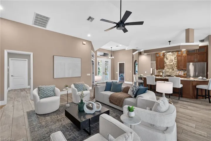 Living room featuring light wood-style floors, a ceiling fan, and a high ceiling