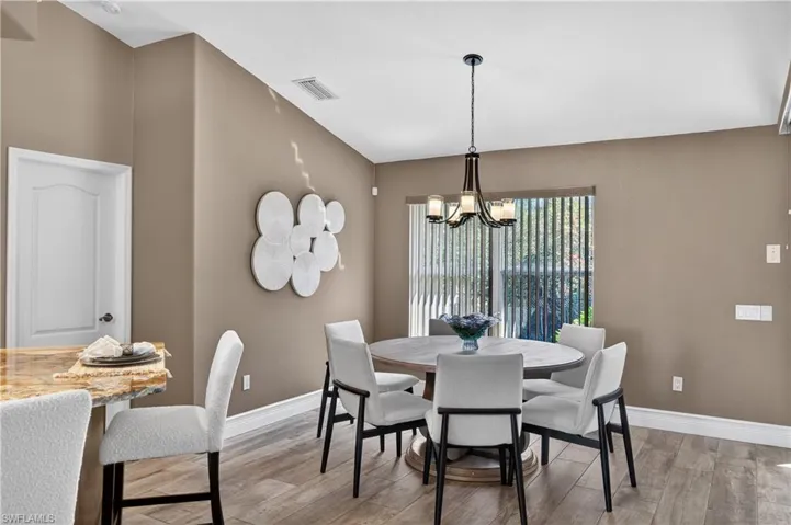 Dining area with light wood-style flooring and suspended lighting