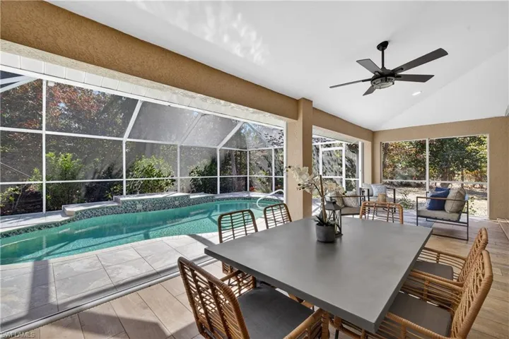 Outdoor pool featuring a sunroom, glass enclosure, a patio area, and outdoor dining area